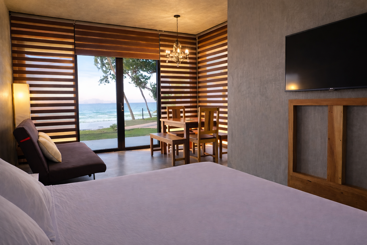 Inside a Shoreline cabin, bed, dining, and lounge with glass doors to the sea