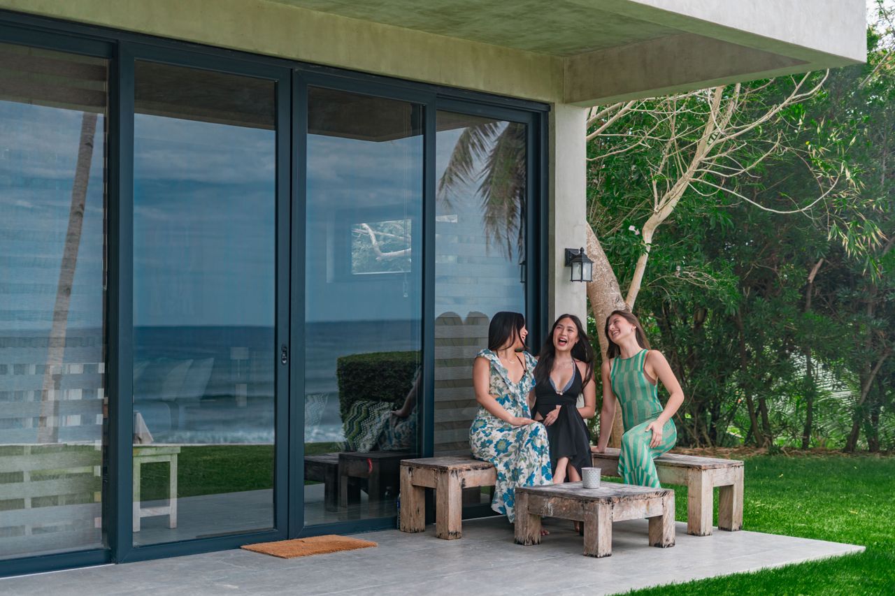 Friends laughing together on the porch of a Shoreline cabin by the sea