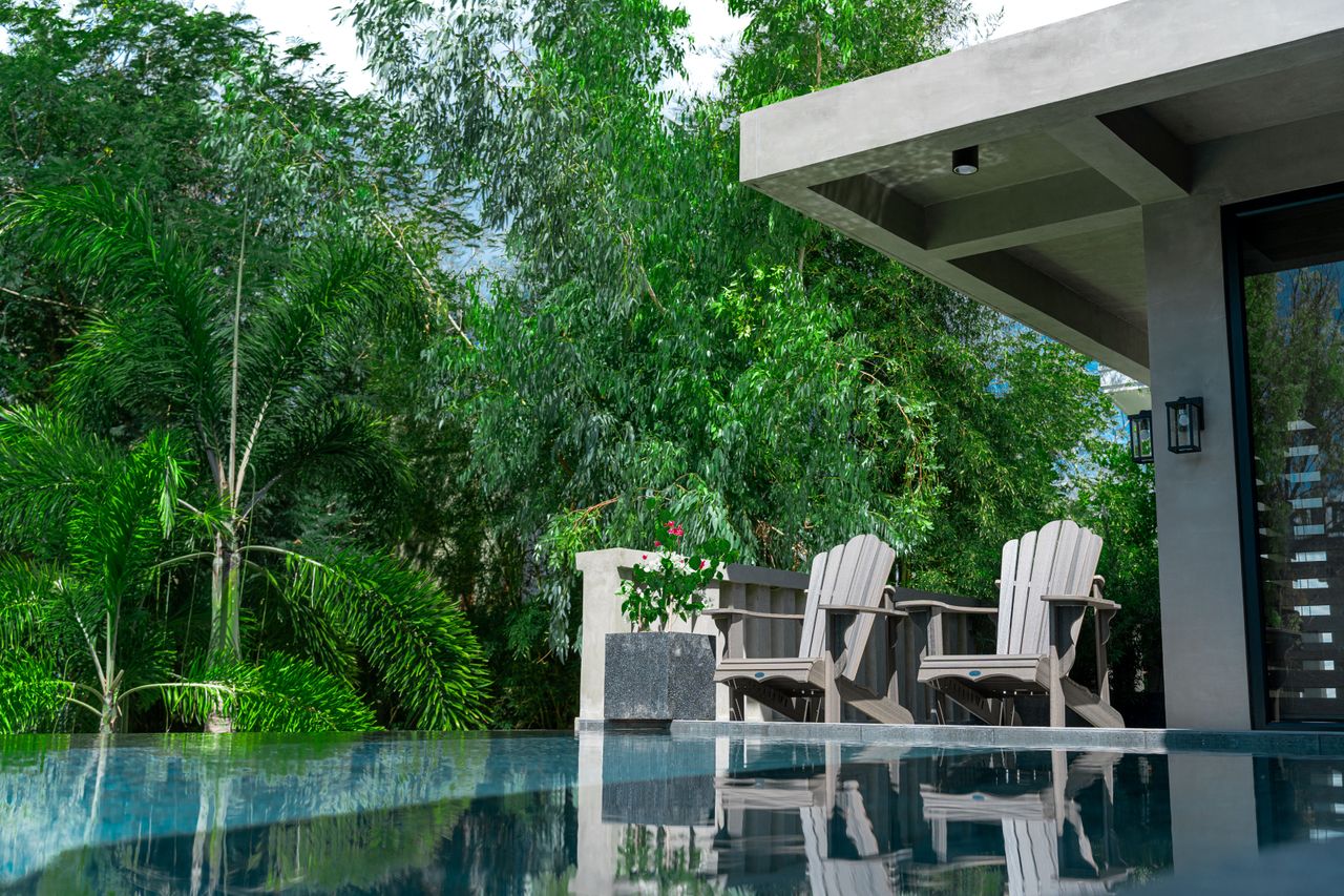 Two Adirondack chairs by the Horizon pool surrounded by lush greenery