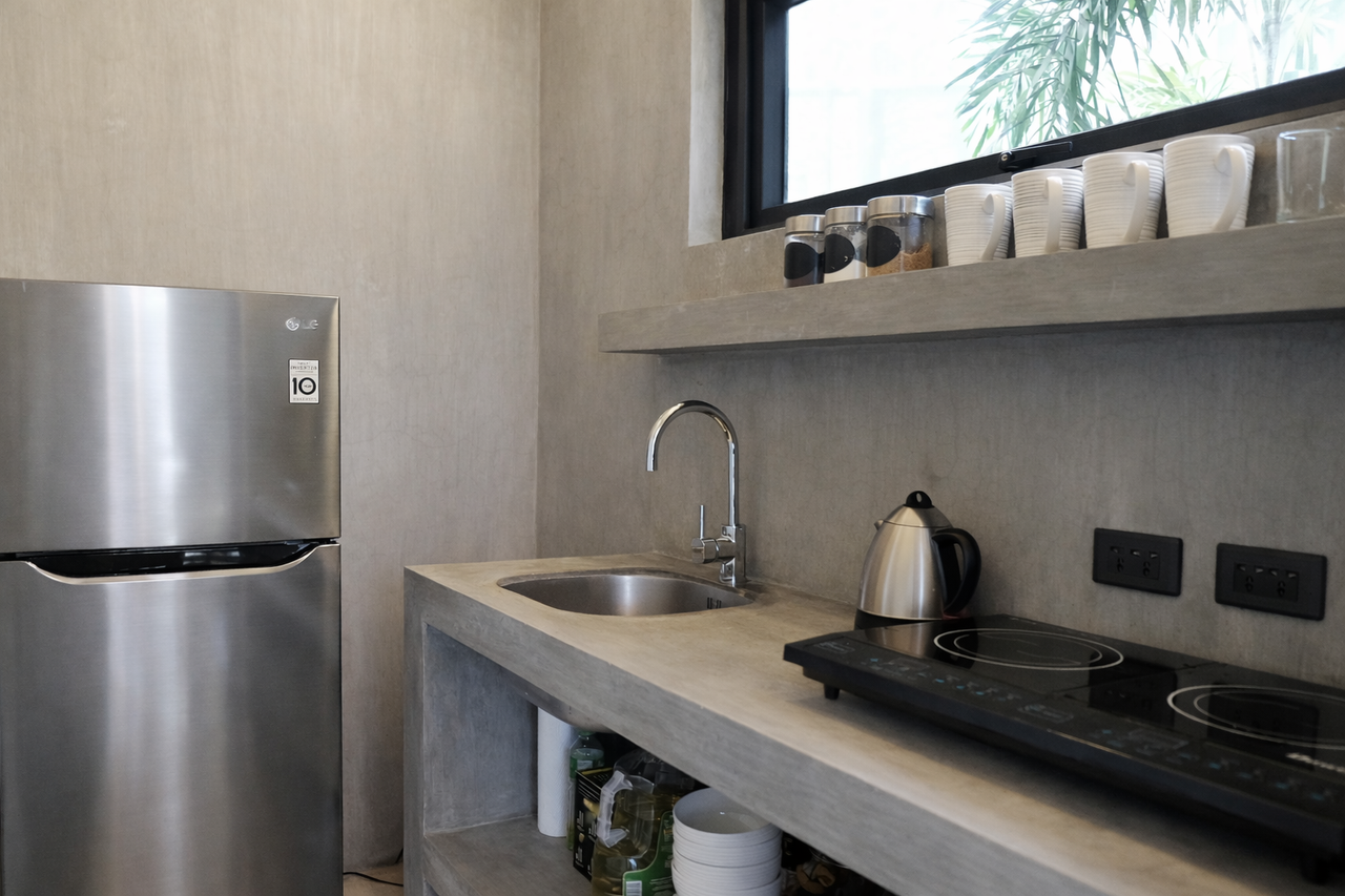 A complete cabin kitchen with fridge, induction cooktop, sink, and kettle