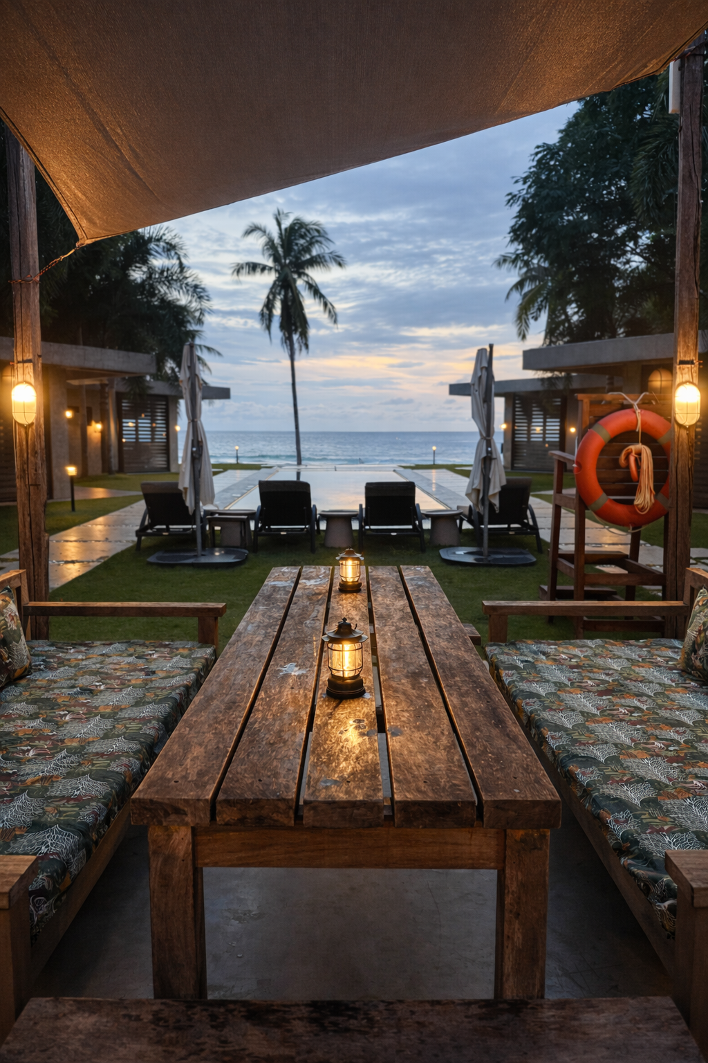 The covered outdoor dining cabana at dusk, framing the pool and sea
