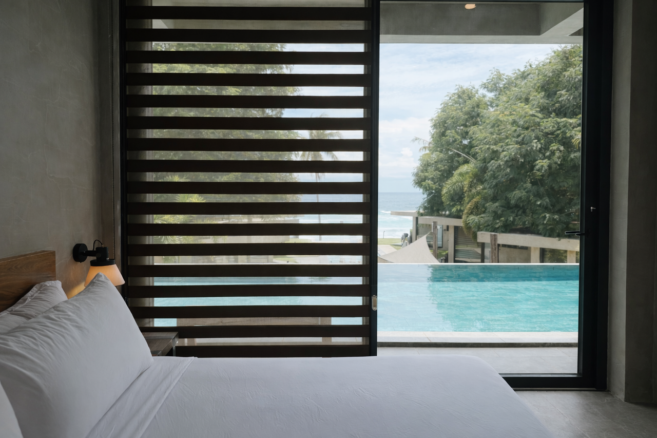 A Horizon bedroom looking out through glass to the infinity pool and the beach