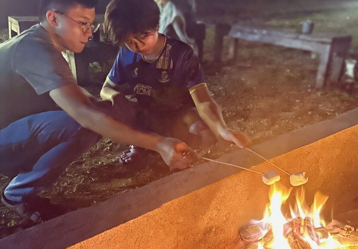 Kids roasting marshmallows over the firepit in the front lounge at night