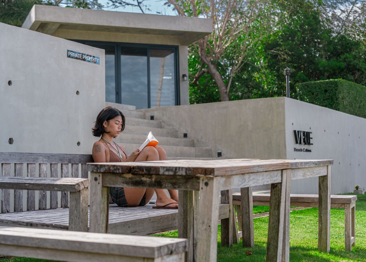 A guest reading alone at a quiet table on the Veue lawn
