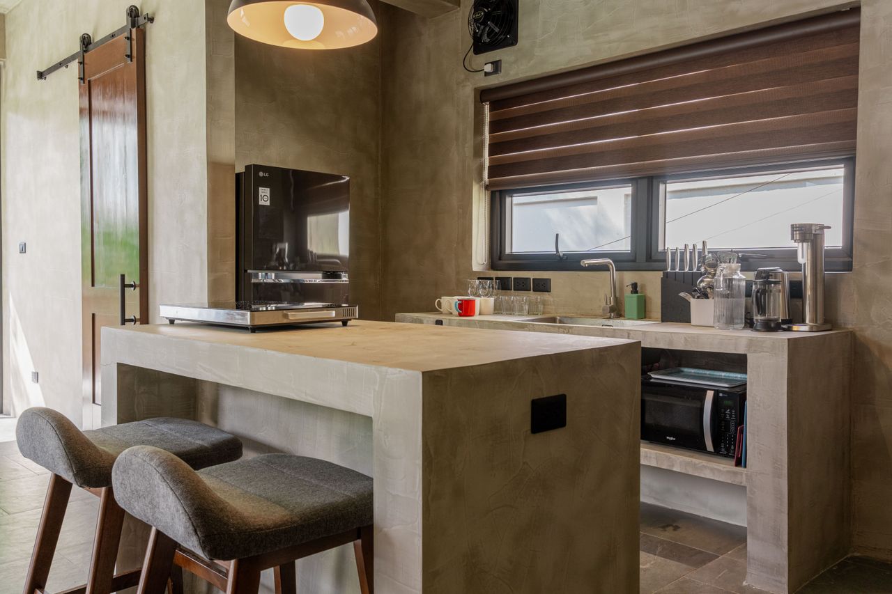 A Horizon kitchen island with bar stools, sink, fridge, and microwave