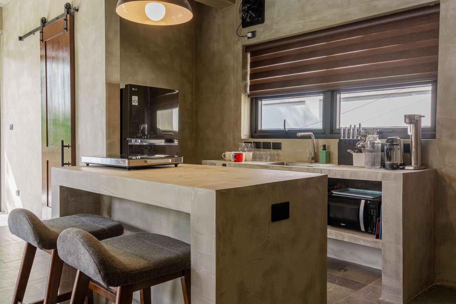 A Horizon kitchen island with bar stools, sink, fridge, and microwave